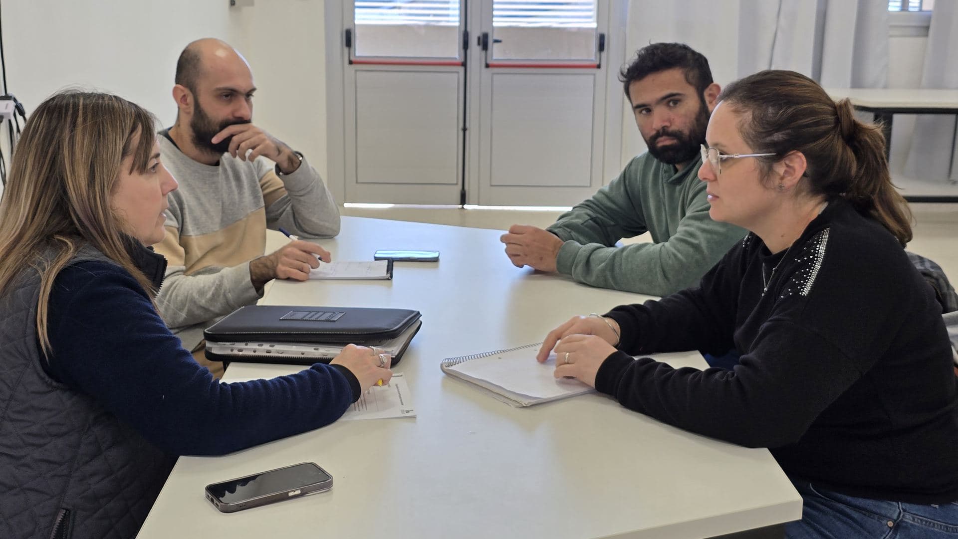 Emprendedores reunidos con mentores alrededor de una mesa de trabajo
